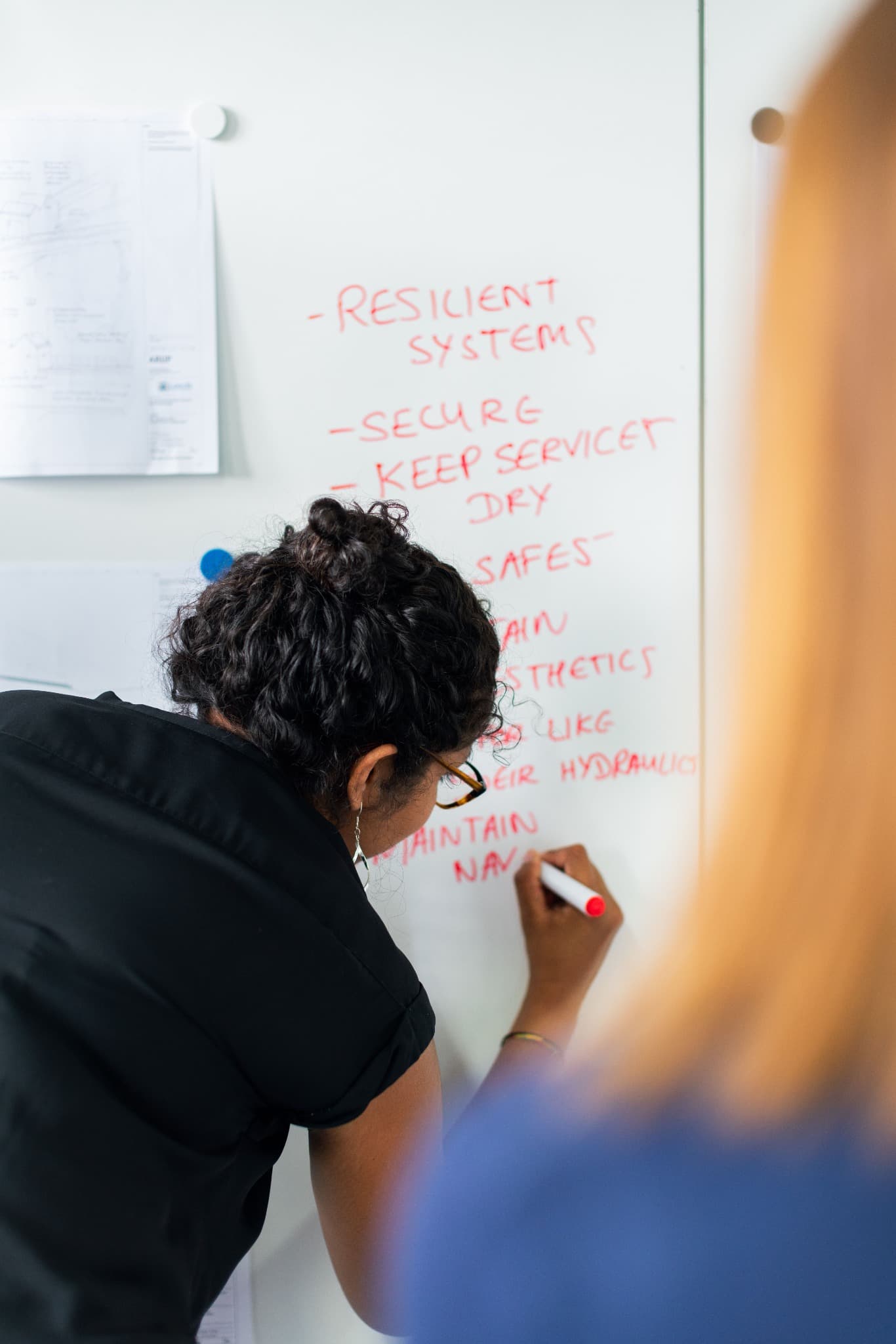 An engineer writing meeting notes on a whiteboard